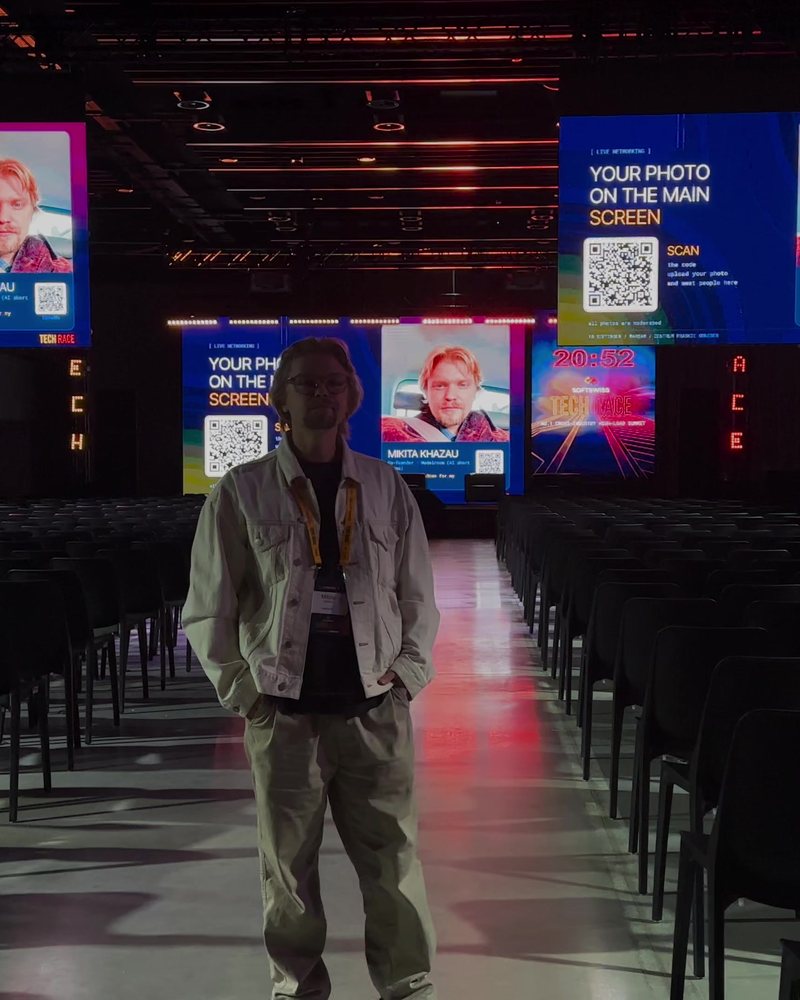 Tech Race Summit: a guest standing in the hall next to his own card on the main screen